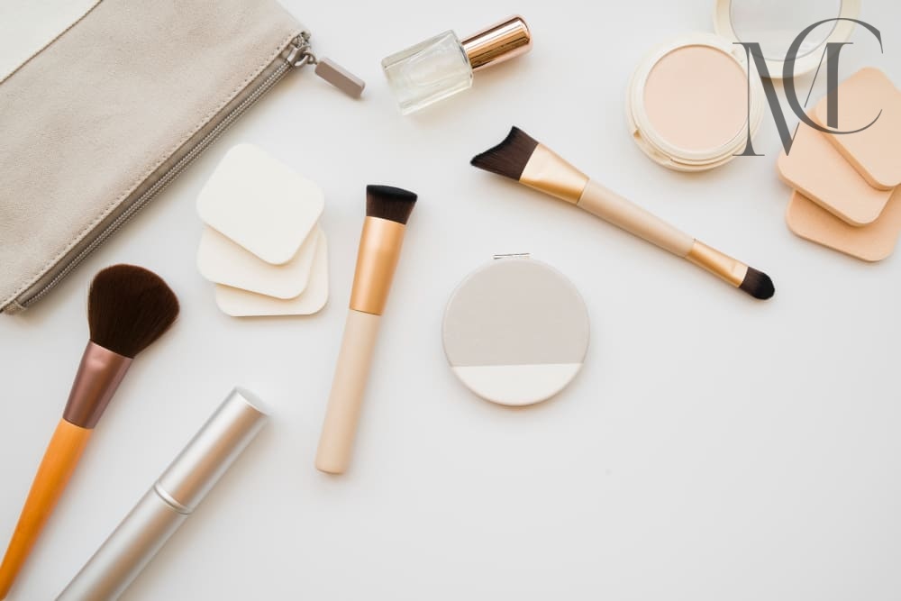 4-in-1-makeup-brushes (1) Overhead shot of makeup brushes, sponges, compacts, a tube of mascara, nail polish, and a makeup bag on a white background.