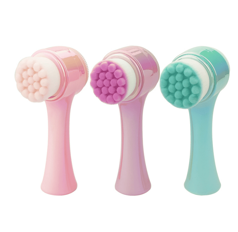 Three pastel-colored facial cleansing brushes with soft bristles.