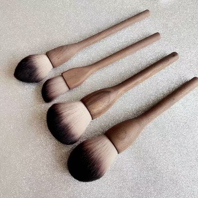 Four makeup brushes with wooden handles and ombre bristles.