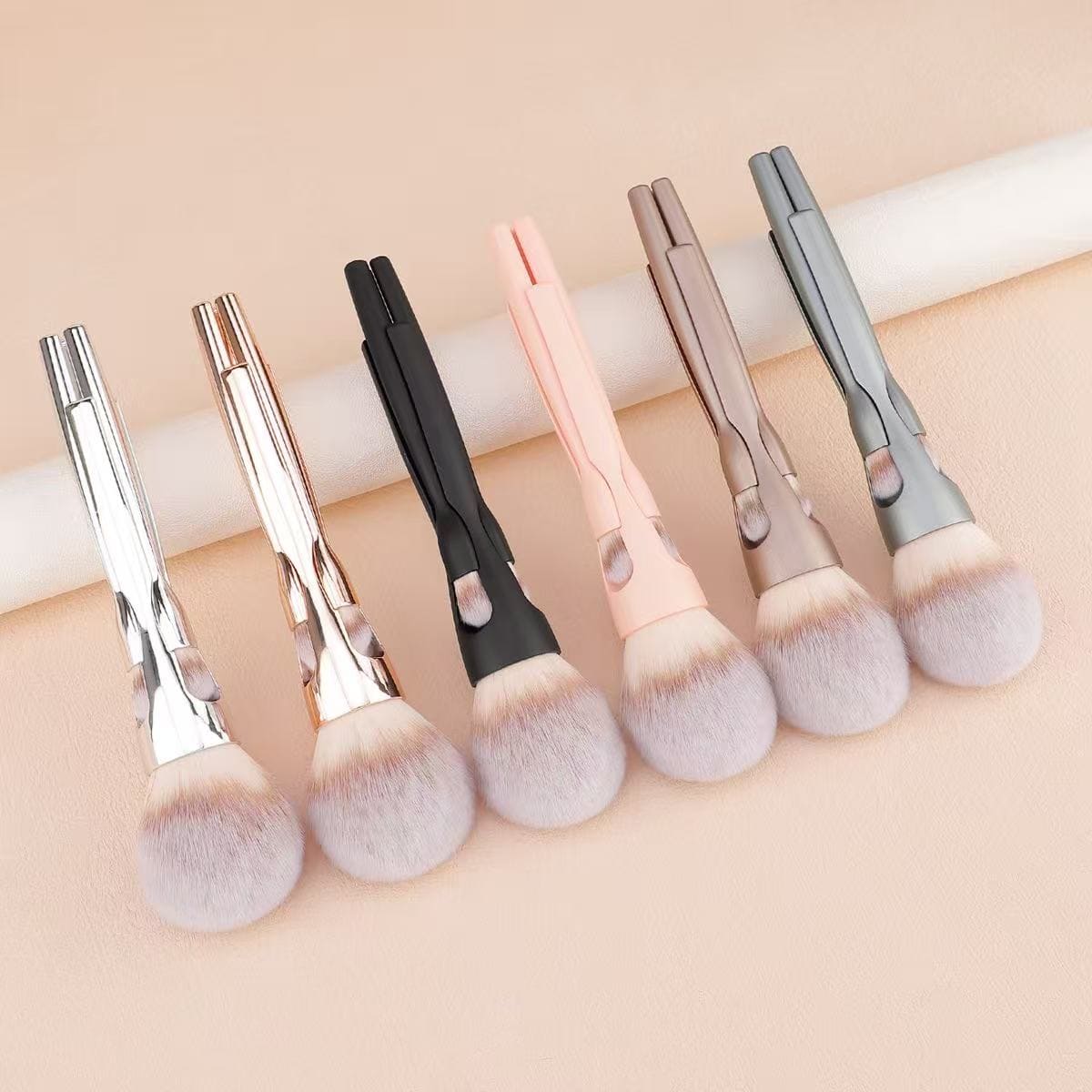 Set of six modern makeup brushes in various handle colors.