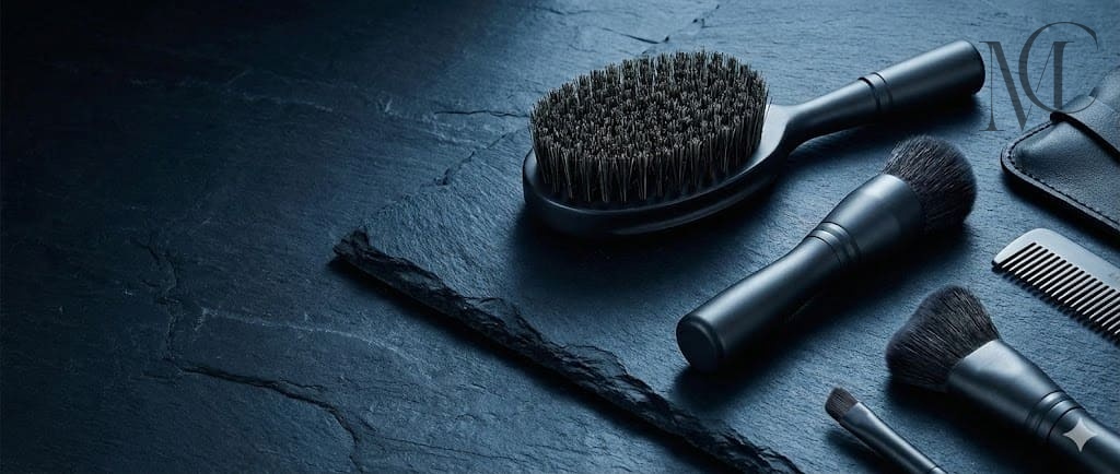 men's makeup brush Black grooming kit on a dark slate background.