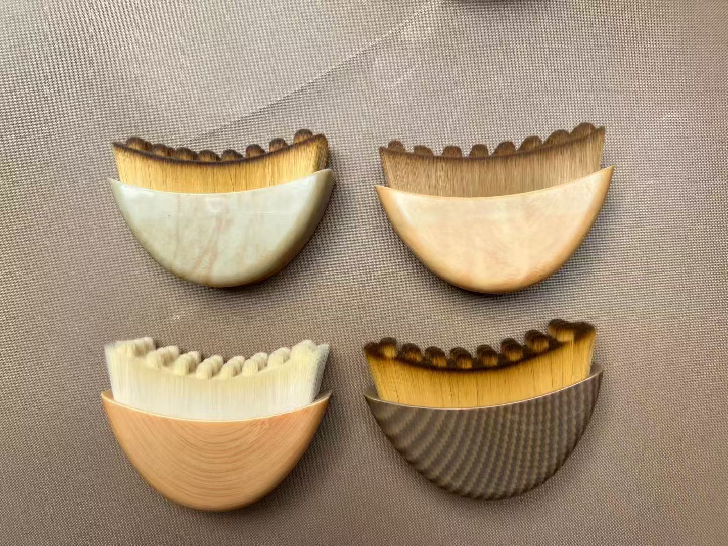 Four crescent-shaped makeup brushes with different handle materials and bristle colors.