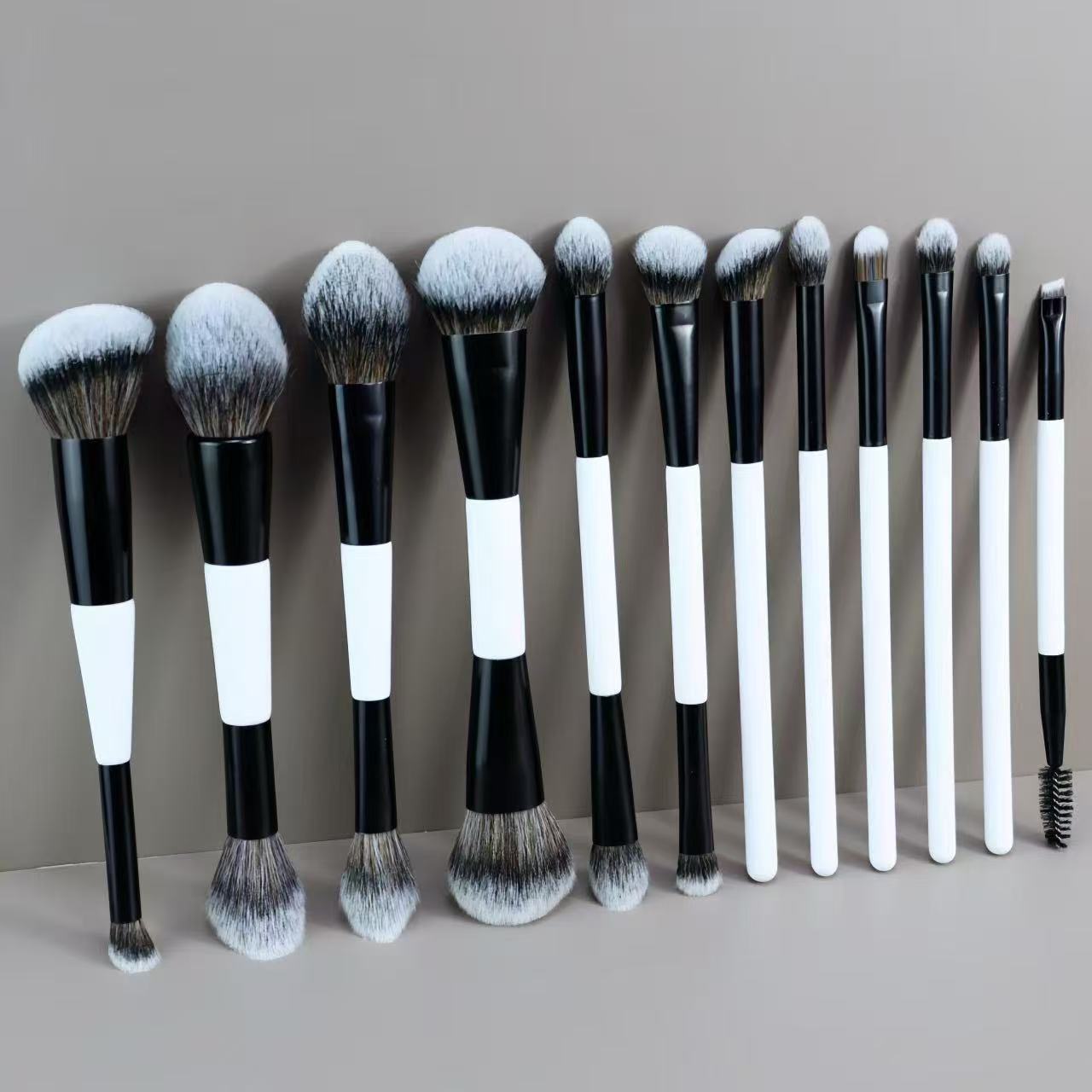 Set of 12 black and white makeup brushes with various sizes and shapes.