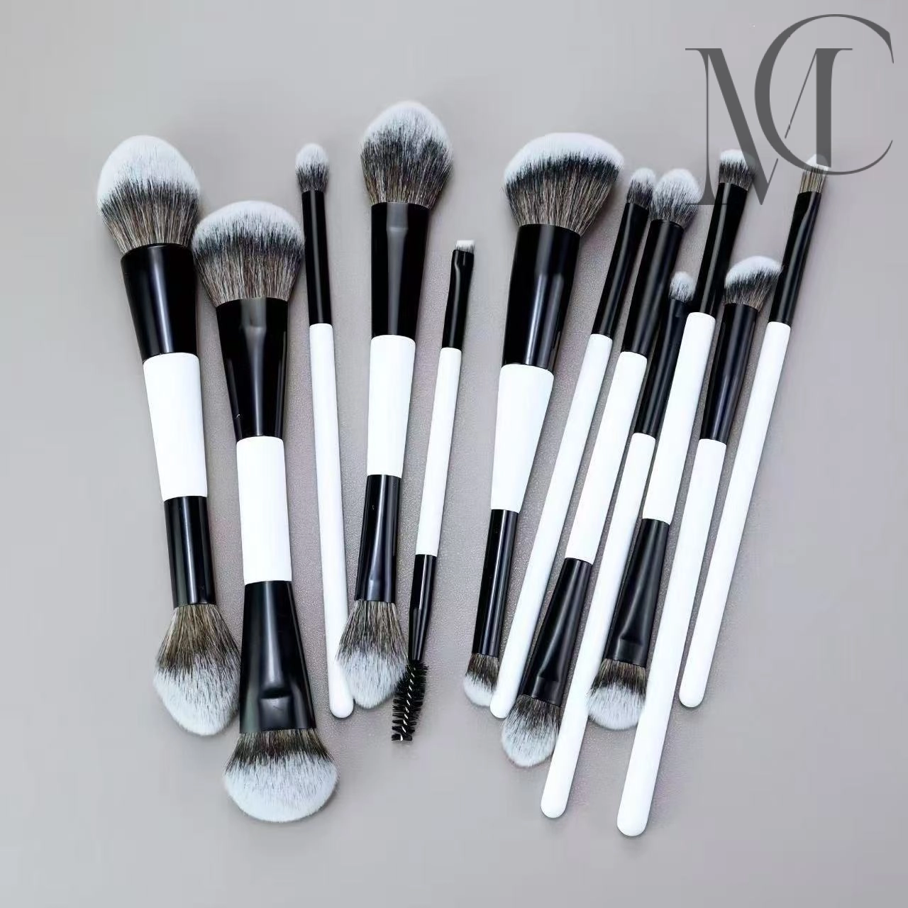 Dual-Ended Pro Makeup Brush A collection of makeup brushes with black handles and white tips, arranged on a gray surface.