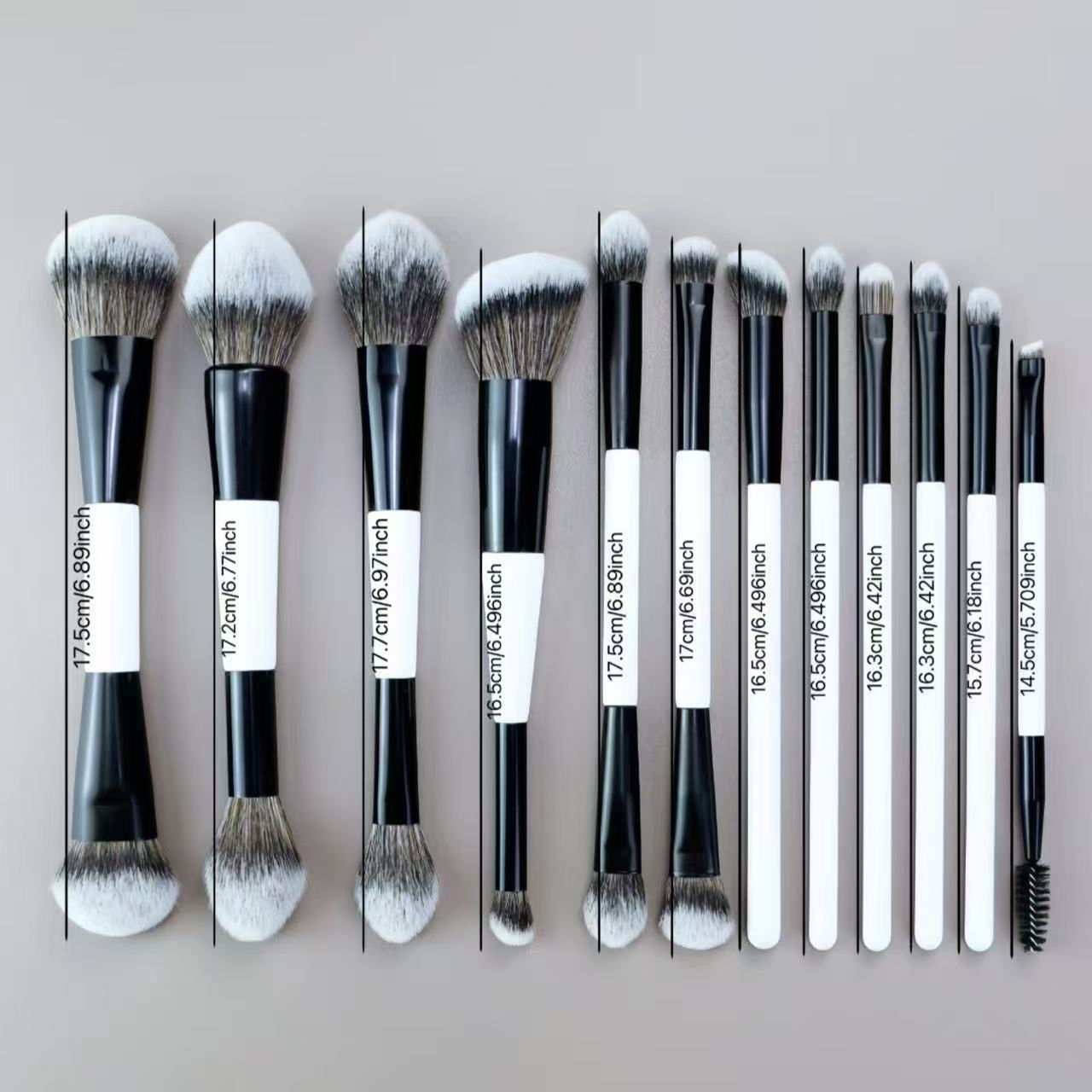 A set of 12 black and white makeup brushes of various sizes and shapes.