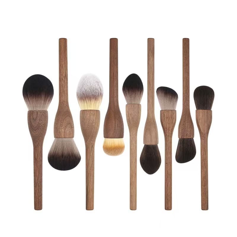 Set of eight makeup brushes with wooden handles, arranged vertically against a white background.